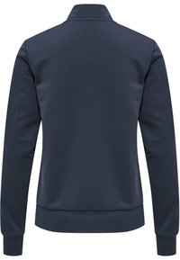 Tummansininen takki, jossa on korkea kaulus, pitkät hihat ja joustavat hihansuut. Sileä pinta, muotoon ommeltu malli ilman näkyviä koristeita.