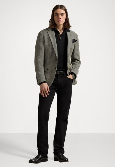 Gray herringbone blazer, black polo shirt, black jeans, and black leather shoes. Notable pocket square detail, smooth textures.