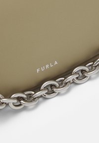 Borsa in pelle beige con tracolla in catena argentata. Il nome del marchio "Furla" è stampato in bianco sulla superficie.