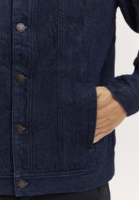 Navy denim jack met zilveren knopen, dubbele borstzakken, zijhandzakken en een klassieke kraag, met een gestructureerde, textuurafwerking.