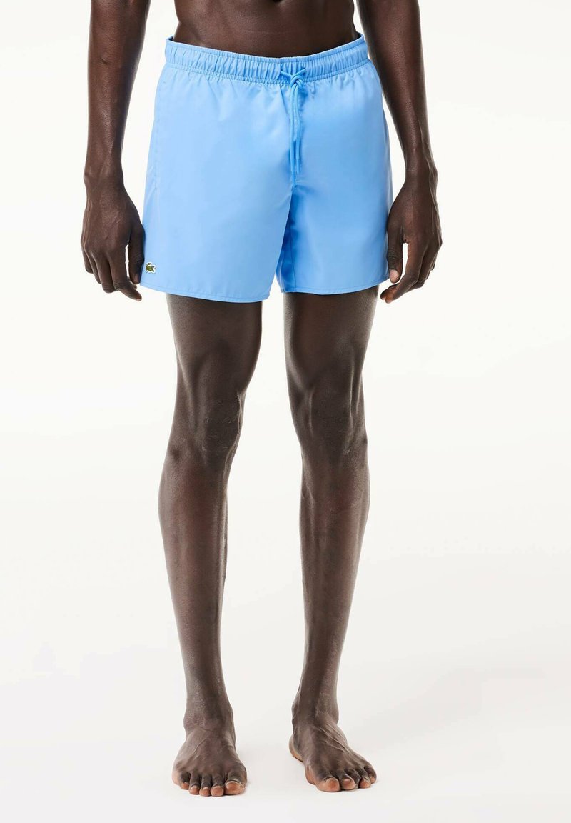 Jasnoniebieskie kąpielówki z elastycznym pasem, sznurkiem do regulacji oraz małym logo. Gładka tekstura i krój sięgający powyżej kolan.