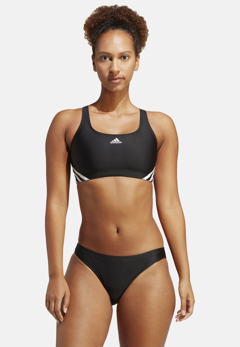 Zwarte sportieve bikini-top met brede bandjes en witte zijaccenten. Bijpassende zwarte bikini-broekjes. Gladde textuur, aansluitend ontwerp.