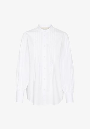 Biała koszula zapinana na guziki z stójką, z długimi, bufkami rękawami, pionowymi plisami z przodu i okrągłym dołem.