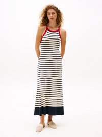 Abito maxi lavorato a maglia con dettagli rossi e strisce blu navy su sfondo bianco. Presenta una parte superiore aderente e un orlo svasato. Abbinato a scarpe slip-on in tessuto intrecciato.