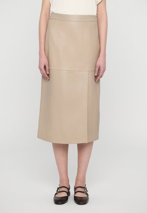 Beige skinn midi-skjørt med en glatt tekstur, sidelommer og synlige sømdetaljer. Kombinert med mørkebrune stroppesko.