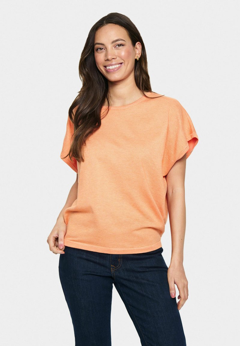 Top arancione a maniche corte in un morbido tessuto testurizzato con una vestibilità comoda. Abbinato a jeans di denim scuri. Scollo tondo semplice, design casual.