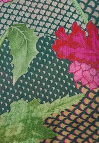 Green and beige patterned fabric with large green leaves and pink-red flower motifs layered on top.