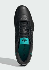 Black leather sneaker with turquoise accents, textured upper, and six black laces. Features logo on tongue and insole. Rounded toe design.