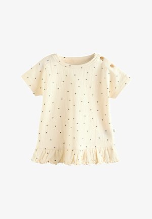 Krém színű, rövid ujjú ing kis fekete szívmintákkal és fodros szegéllyel. Két fa gomb található a vállán. Strukturált anyag.