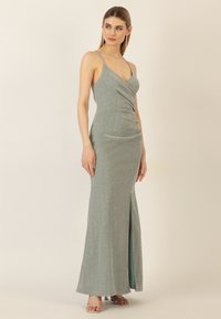 Metallisches türkisfarbenes Abendkleid mit einem drapierten Oberteil und dünnen Trägern; verfügt über einen seitlichen Schlitz und eine figurbetonte Silhouette, die bis zum Boden reicht.