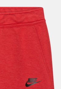 Rote Baumwoll-Sweatpants mit einem schwarzen Nike-Logo. Der Bund ist elastisch, mit Seitentaschen und einer weichen, strukturierten Oberfläche.