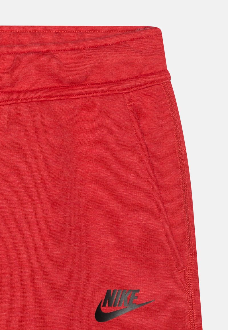 Rote Baumwoll-Sweatpants mit einem schwarzen Nike-Logo. Der Bund ist elastisch, mit Seitentaschen und einer weichen, strukturierten Oberfläche.