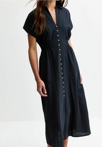 Abito blu scuro, con bottoni, maniche corte e vita elastica, caratterizzato da una linea dritta e una leggera lucentezza.