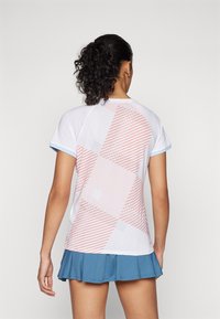 Kurzärmliges weißes Sportshirt mit orange-grauem geometrischem Muster, blauen Akzenten an den Ärmeln und einem leichten, strukturierten Stoff.