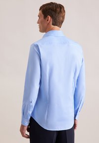 Camicia azzurra a maniche lunghe con colletto classico, polsini con bottoni e orlo curvo. Tessuto morbido con dettagli di design minimi.