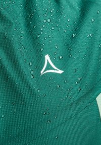 Zielony, teksturowany materiał z kroplami wody. Zawiera białe logo przypominające trójkąt, umieszczone po prawej stronie.