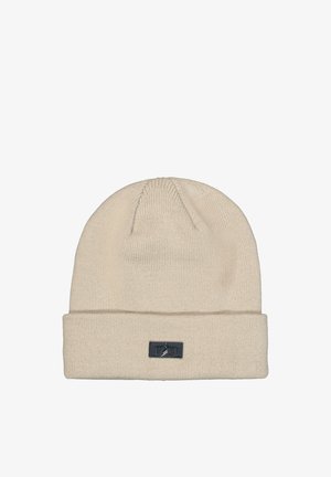 Beige knit beanie hat with folded cuff and small black rectangular logo patch on front center.