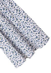 Tessuto bianco con un motivo testurizzato caratterizzato da piccoli fiori blu e foglie verdi, disposti densamente su tutta la superficie.