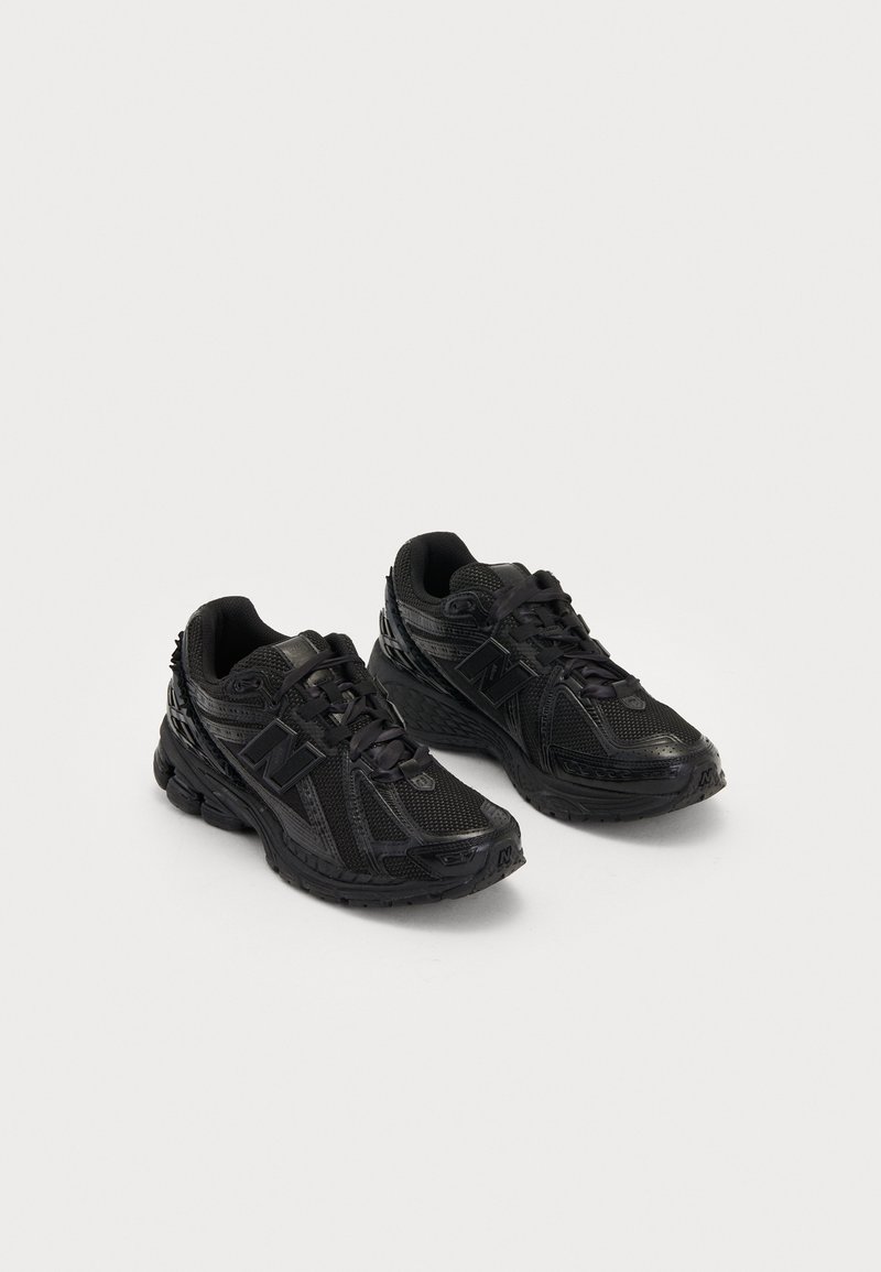 Black athletic shoes made of mesh and synthetic materials. Features a cushioned sole, textured patterns, and embossed branding on the side.