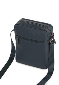 Bolso cruzado azul marino hecho de material suave, con dos compartimentos con cremallera, un bolsillo frontal y una correa ajustable.