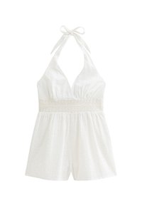 Witte halterneck romper van textuurstof, met kanten rand op de taille en losse shorts. Heeft een striksluiting bij de hals.
