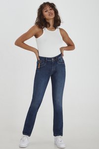 Jeans de mezclilla azul oscuro con un diseño de pierna recta, estilo de cinco bolsillos y un sutil acento marrón en la parte delantera. Combinados con una camiseta sin mangas blanca.