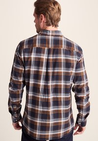 Men's plaid shirt in navy blue, white, and orange. Features long sleeves, button cuffs, and a classic collar with a back yoke design.