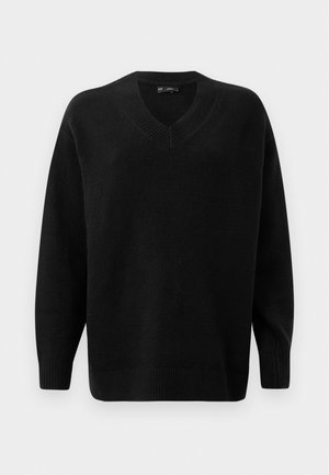 Pull noir en V fabriqué en matériau tricot doux. Dispose de manches longues, de poignets et d'un ourlet côtelés, et d'un motif texturé près du col.