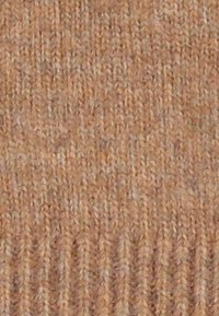 Tan knitted fabric featuring a textured pattern with raised ridges. The surface appears soft and slightly irregular, adding visual interest.