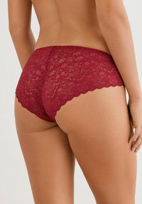 Burgunderfarbene Spitzen-Hipster-Unterwäsche mit gewellten Kanten, die ein florales Muster und eine halbtransparente Textur für zusätzliche Details aufweist.
