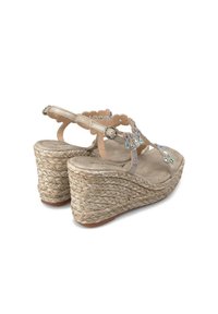 Sandales compensées beiges avec texture en jute tissé, comprenant des strass décoratifs et un design de bride à bords ondulés, talon ouvert avec boucle ajustable.