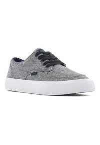 Sneaker in tela grigia con lacci neri, suola in gomma bianca e tessuto testurizzato. Presenta un design low-top e una sottile marca laterale.