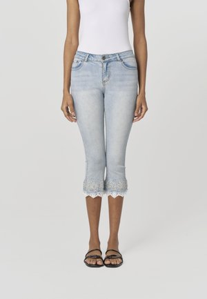 Lichtblauwe cropped jeans met een geschulpte kanten zoom met bloemenpatronen. Gecombineerd met zwarte teenslippers. Klassiek ontwerp met 5 zakken.