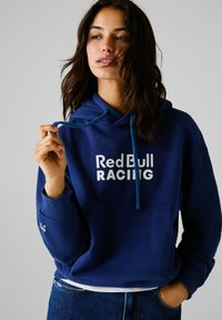 Hoodie bleu en mélange de coton, avec une poche avant et un capuchon à cordon. Logo "Red Bull RACING" en blanc sur la poitrine. Coupe décontractée.