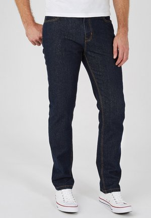 Donkerdenim jeans met een rechte snit, lichtere stiksels en een vijf-pocket ontwerp, gecombineerd met witte sneakers met rode accenten.