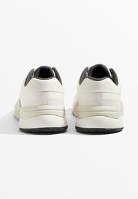 Białe buty sportowe z teksturowaną tkaniną na cholewce i szarymi akcentami. Posiadają amortyzowaną podeszwę i gumową podeszwę z wzorem.