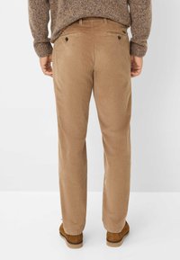 Tan corduroy broek met een rechte snit, met een gestructureerd oppervlak, achterzakken met knoopsluitingen, gecombineerd met bruine schoenen.