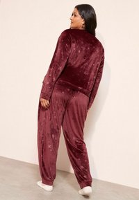 Set de loungewear din velur burgund, cu motive de stele, mâneci lungi și pantaloni tapered. Textură moale, cu manșete și talie elastice.