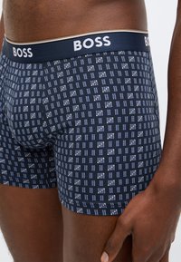 Tengerészkék boxeralsó világoskék és fehér rácsmintával. Rugalmas derékrész "BOSS" felirattal. Puha, rugalmas anyag.