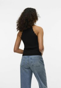 Top nero con scollo all'americana e bordi scallopati abbinato a jeans chiari a vita alta, con tasche posteriori e un taglio morbido.
