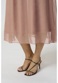 Damm rosa semi-transparent klänning med ett lager av fåll. Matchas med olivgrön högklackad sandal med remmar, med fyrkantig tå och ankelsnygg.