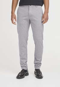 Grå skræddersyede bukser med en glat tekstur, tilspidsede ben, et subtilt meleret mønster og en enkelt knap ved linningen. Bruges med sorte sko.