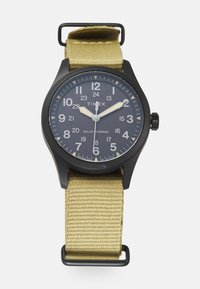 Timex solarni sat s crnim okruglim plastičnim kućištem, tamnoplavim brojčanikom, bijelim arapskim brojkama i svijetlosmešavom tkaninom.