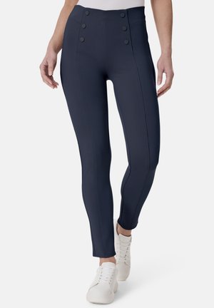Navy-hochgeschnittene Leggings mit glatter Textur, ausgestattet mit vier dekorativen Knöpfen und vertikalen Nahtdetails, getragen mit weißen Turnschuhen.