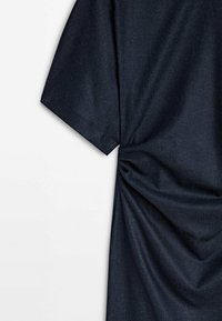 Dunkelblaues Stoffkleidungsstück mit kurzen Ärmeln und einer gerafften Detail seitlich, das Textur schafft. Glatte Oberfläche, minimalistisches Design.