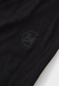 Sort stof med en blød tekstur, prydet med et subtilt hævet logo, der læser "Buff" i et cirkulært design, orienteret mod nederste højre hjørne.