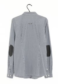 Svart och vit rutad långärmad skjorta med armbågsflickor, knappad krage och justerbara manschetter. Tillverkad av tyg med en slät textur.