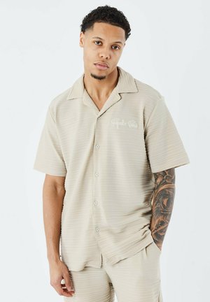 Beige overhemd met korte mouwen en knopen, gemaakt van textuurstof, met een effen kraag en geborduurde details op de linkerborst.