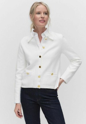 White cardigan with a collared design, gold button details, and front pockets. Made of smooth fabric, it features a cropped fit and long sleeves.