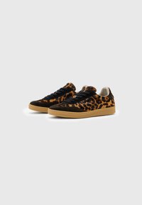 Pareja de zapatillas bajas con cordones negros, parte superior de tela con estampado de leopardo, acentos de ante negro y suelas de goma marrón claro sobre un fondo blanco.